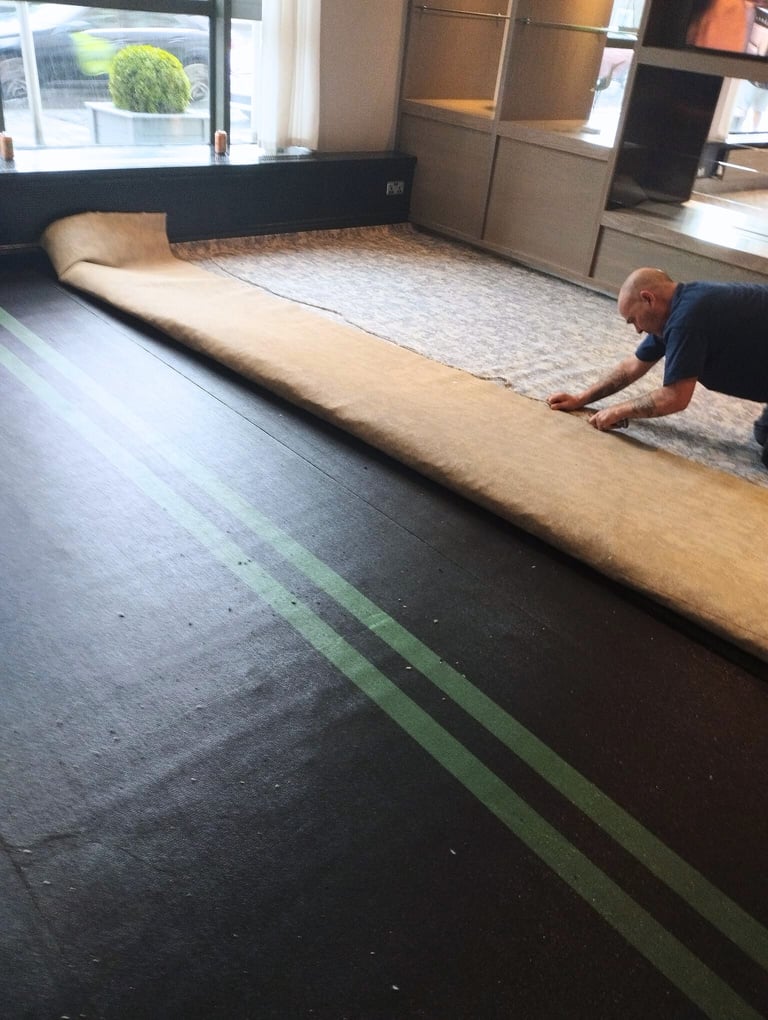 a person is laying down a large piece of carpet on the floor