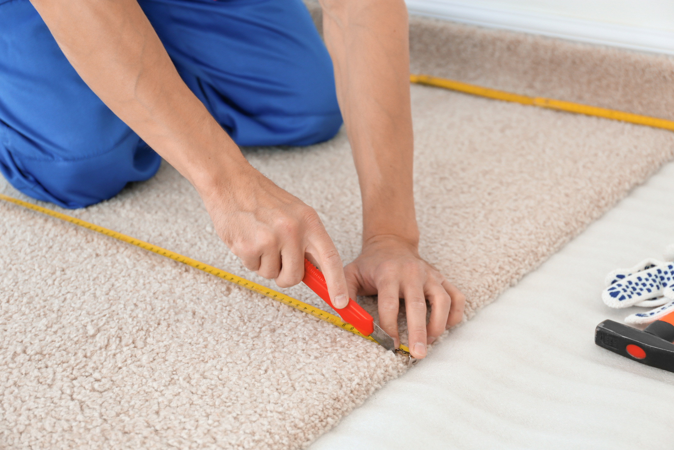 a person using a measuring tape to measure the size of a carpet